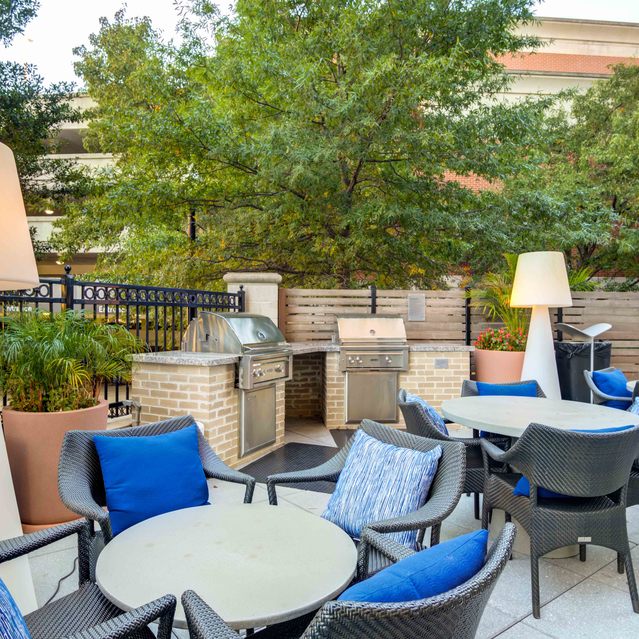 Instrata Pentagon City - Outdoor Patio Area with Round tables and Cushioned Chairs, Tall White Lamps and Grilling Station