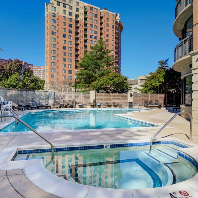 Instrata Pentagon City - Outdoor Swimming Pool and Hot Tub Surrounded By Lounge Chairs, Trees, and Apartment Buildings