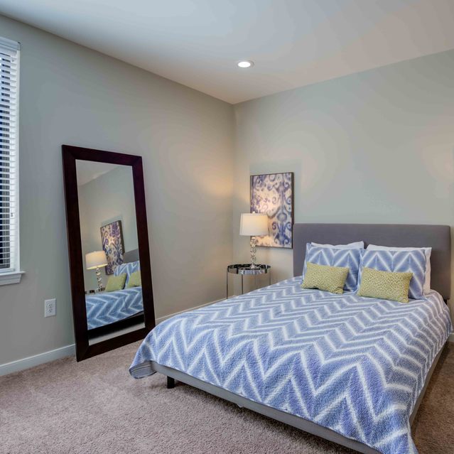 Instrata Pentagon City - Carpeted Bedroom with Two Table Lamps, a Mirror and a Huge Window